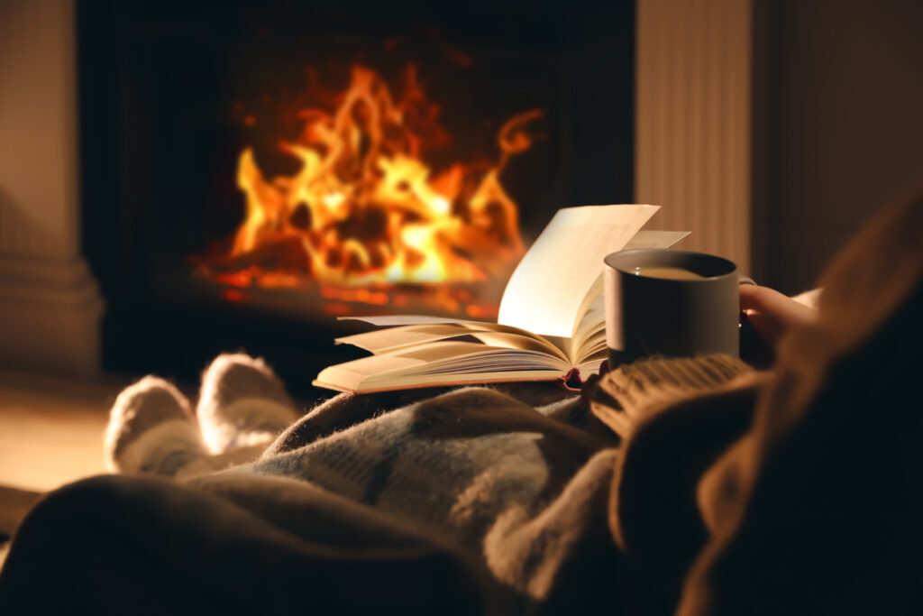 Cozy reading by the fireplace with a warm beverage